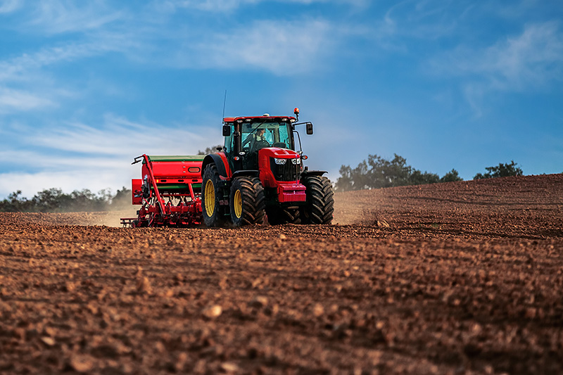 Red farm tractor operating during planting season on Minnesota farmland